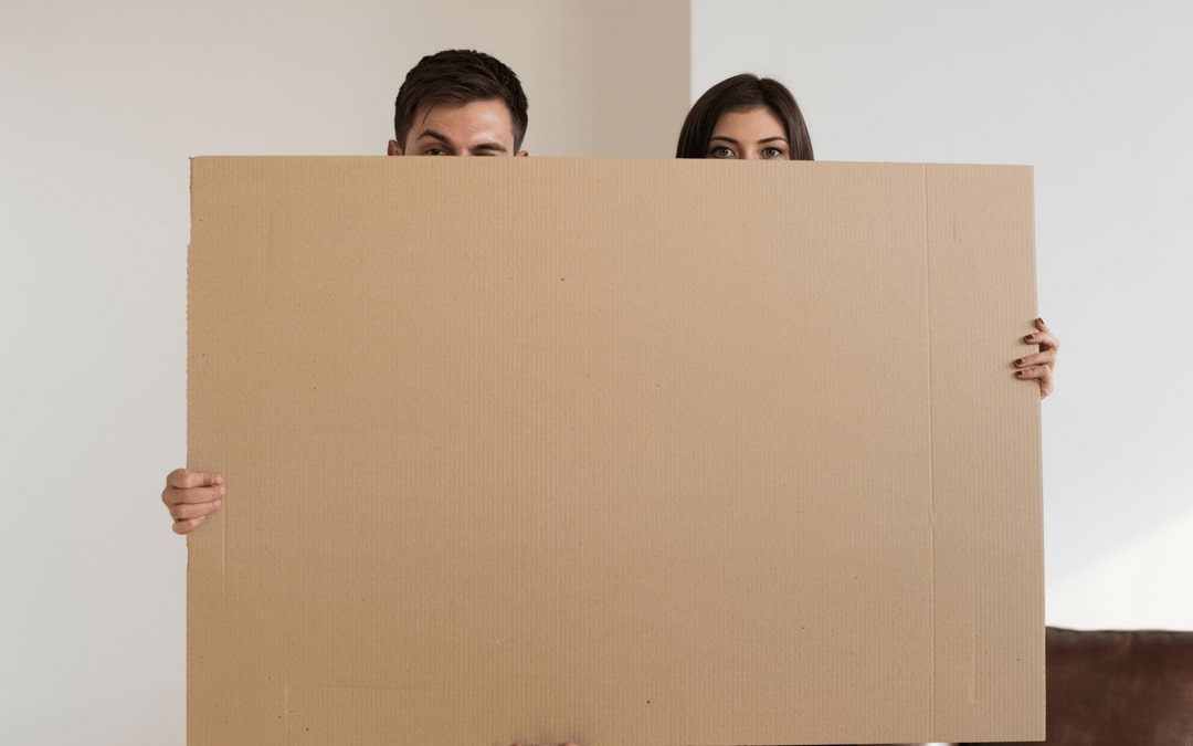 woman and man hiding behind a box