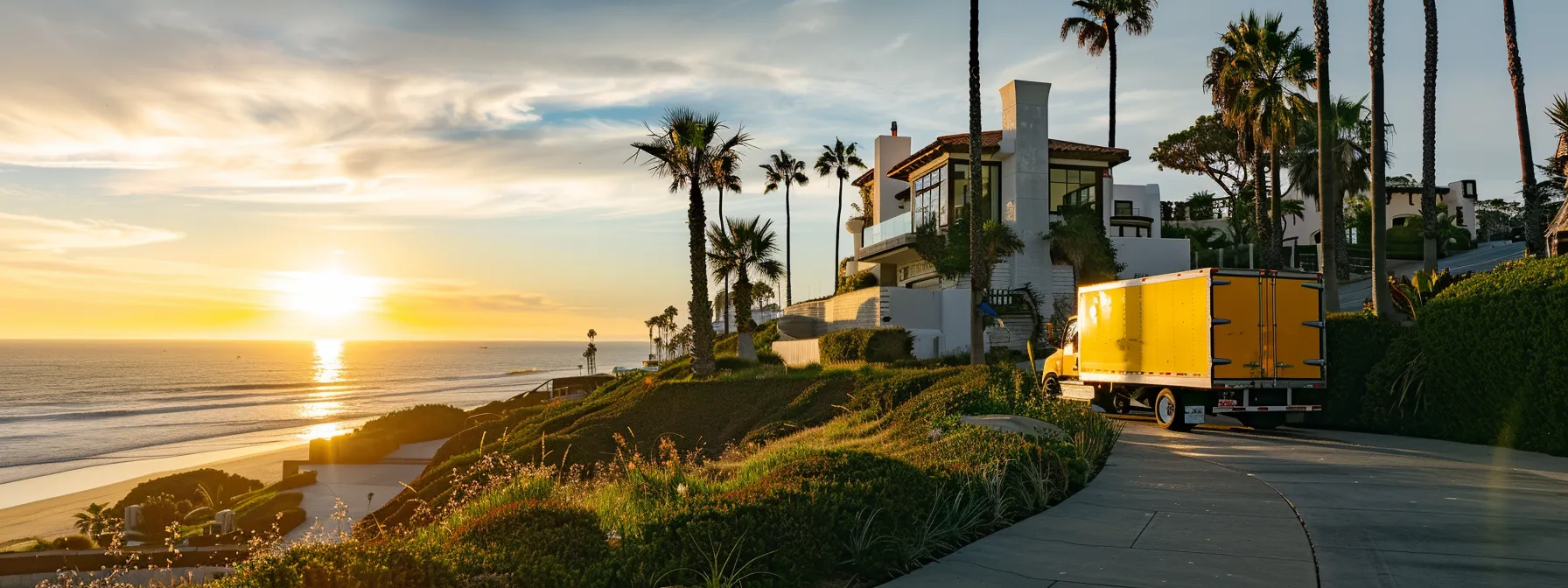 a bright yellow moving truck parked in front of a beautiful san diego beachfront home.