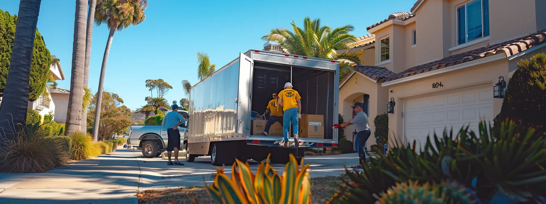 a team of movers carefully loading a colorful moving truck in front of a sunny san diego home.