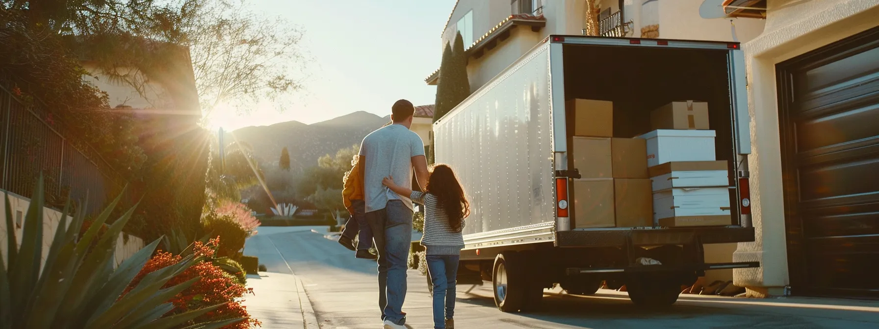 A Family Happily Watching Professional Movers Load A Moving Truck In Front Of A Scenic Los Angeles Backdrop.