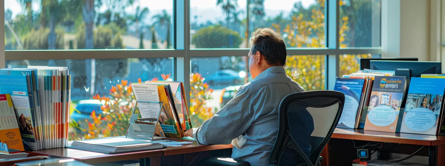 A Customer Sitting At A Desk, Surrounded By Colorful Moving Brochures, Comparing Quotes And Service Options While Enjoying The Sunny View From A Window Overlooking Irvine, Ca.