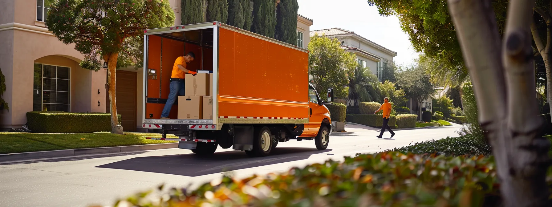 Professional Movers Carefully Loading Boxes Into A Bright Orange Moving Truck In Irvine, Ca (33.6846° N, 117.8265° W) - &Quot;Moving Company Irvine Ca&Quot;